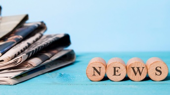 Vier kleine Holzrollen liegen nebeneinander, an den Vorderseiten steht jeweils ein schwarzer Buchstabe, zusammen ergeben sie das Wort 