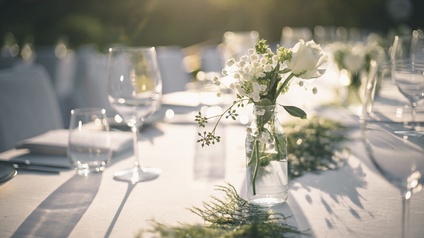 Gedeckter Tisch für eine Feier mit Blumen und Weingläsern.