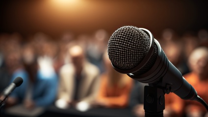 Nahaufnahme eines Mikrofons vor einem Publikum in der Unschärfe