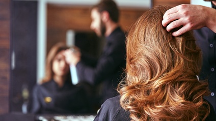 Friseur stylt die Haare der Kundin. 