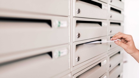 Eine Person steckt einen Brief in einen Briefkasten