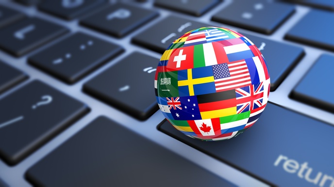 Sphäre mit verschiedenen Länderflaggen auf der Oberfläche liegt auf Computertastatur